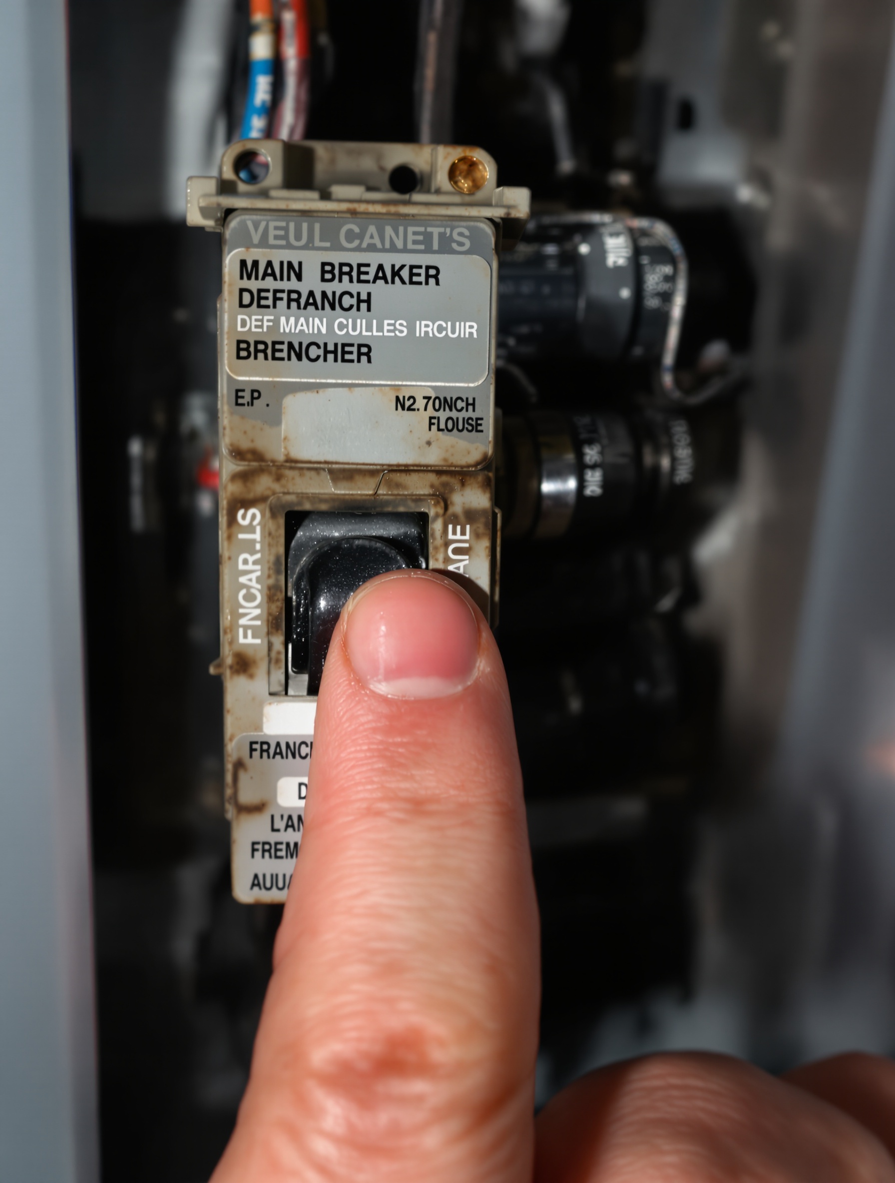Un disjoncteur général en surchauffe avec main hésitante, ambiance stress électrique.