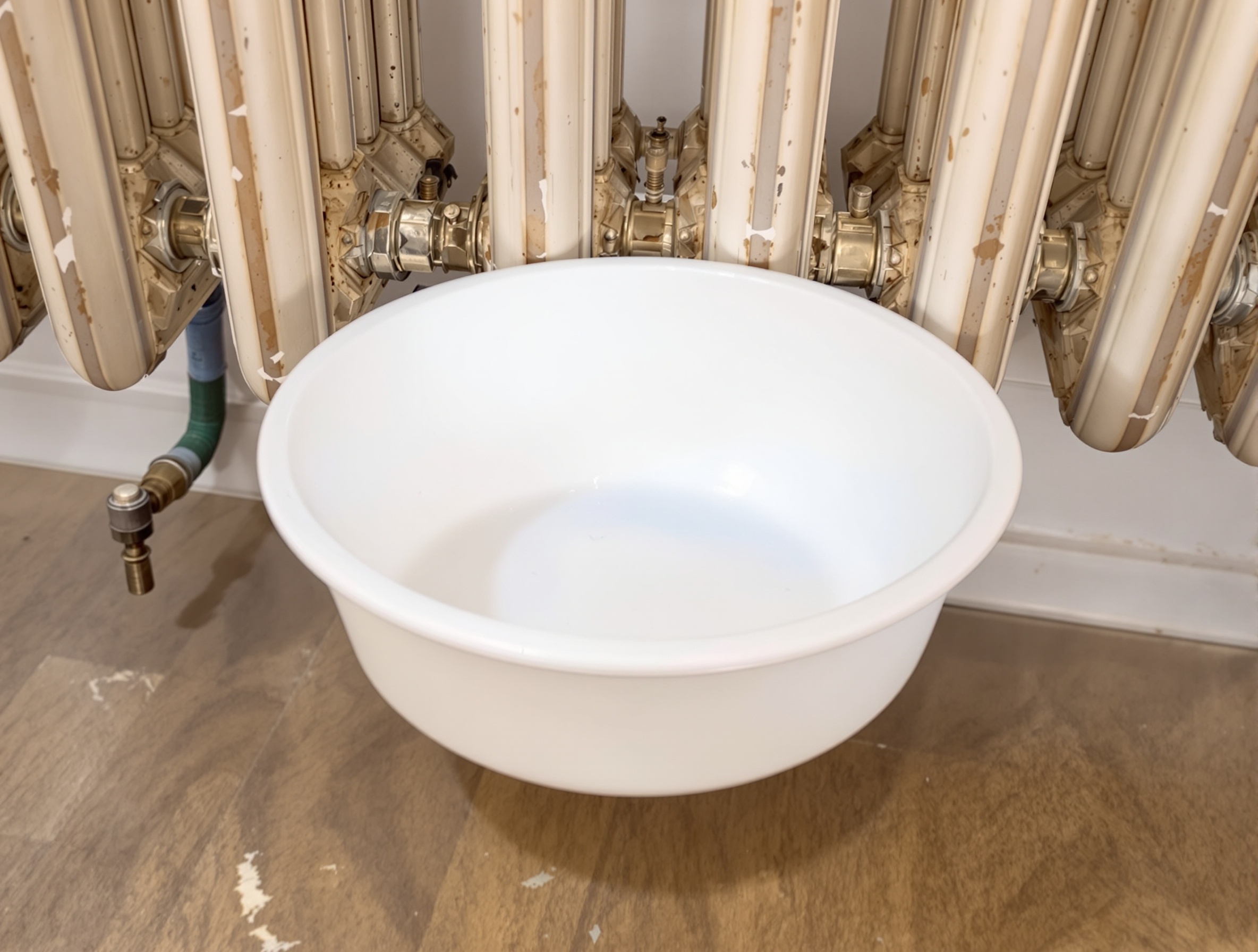 Récipient adapté pour recueillir l'eau lors de la purge d'un radiateur en fonte.