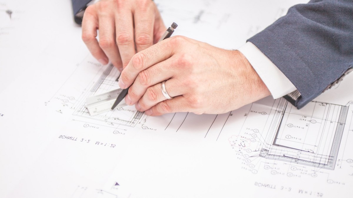 Un architecte étudie des plans de construction sur un bureau de chantier.