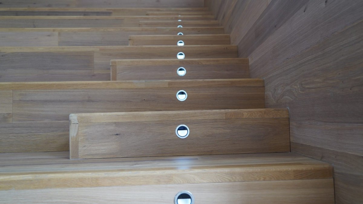 Escalier intérieur en bois avec marches à nez arrondi et contremarches équipées de lampes encastrées