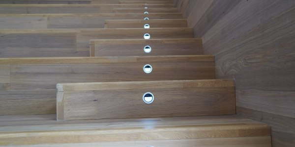Escalier intérieur en bois avec marches à nez arrondi et contremarches équipées de lampes encastrées Escalier intérieur en bois avec marches à nez arrondi et contremarches équipées de lampes encastrées